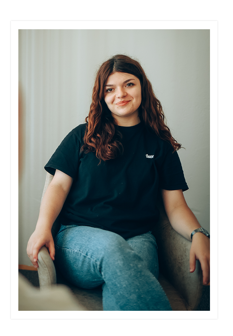 Tochter Viktoria sitzt auf einem Stuhl und lächelt. 