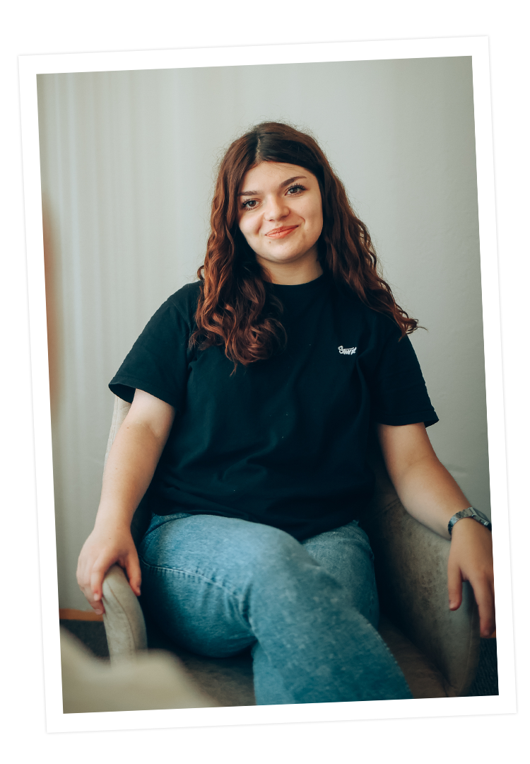 Tochter Viktoria sitzt auf einem Stuhl und lächelt. 