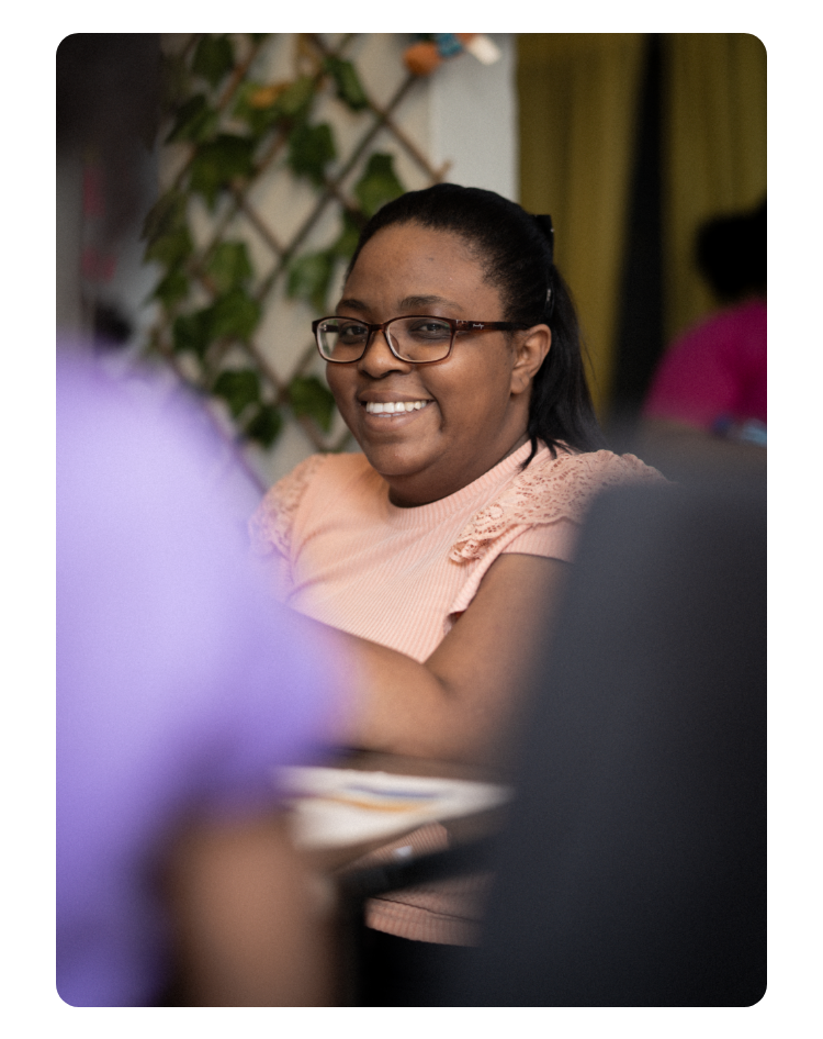 Eine Nahaufnahme von Nora Severino, Sozialarbeiterin der SOS-Kinderdörfer. Sie sitzt an einem Tisch und lächelt in die Kamera. 