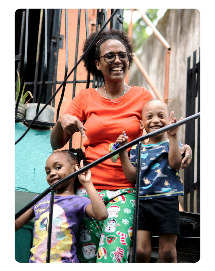 Ein Foto von Evelin Martinez mit ihren beiden Kindern auf einer Treppe. Alle drei lachen fröhlich in die Kamera. 