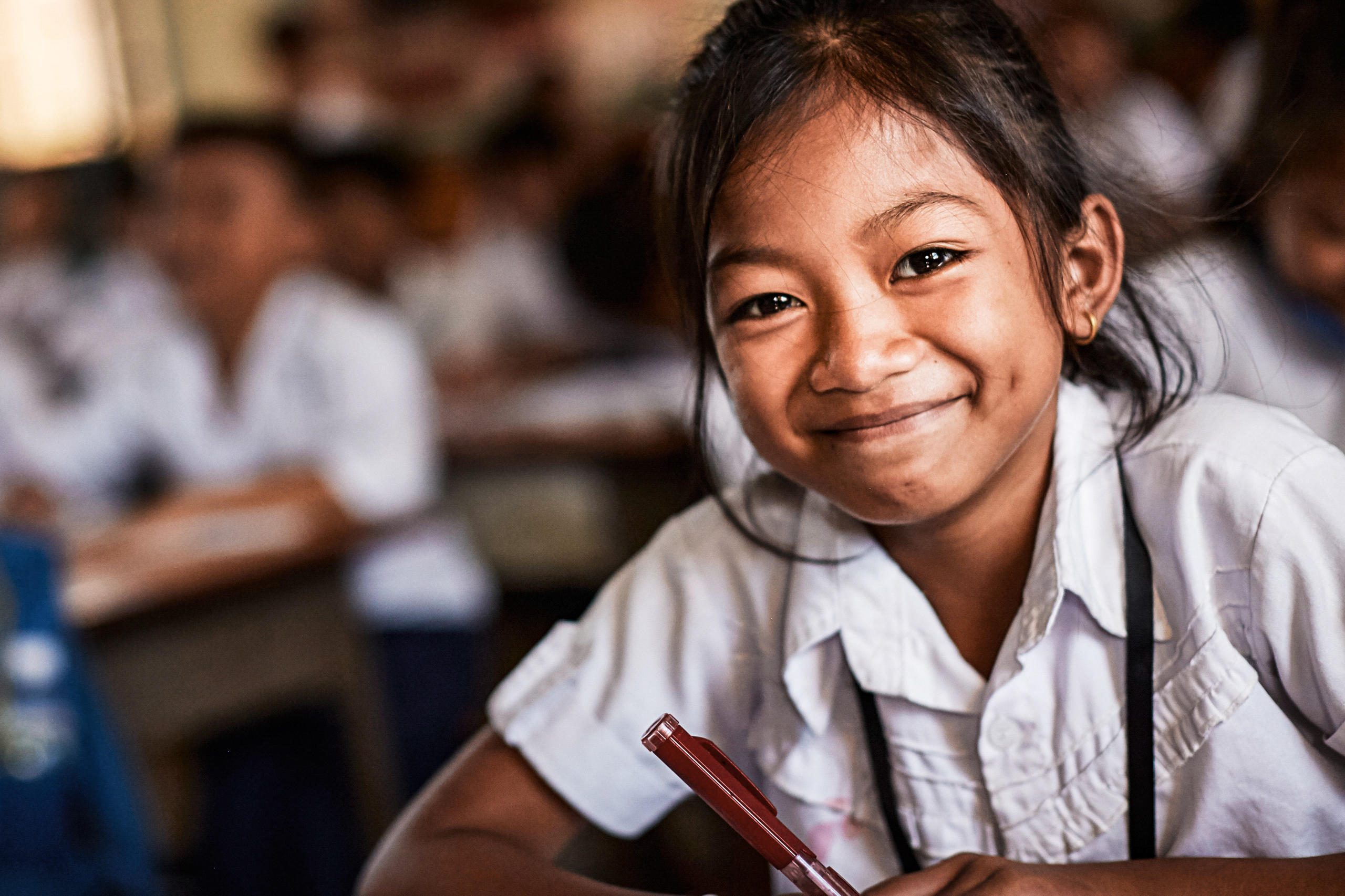 Mädchen, ein Patenkind, sitzt an Schulbank und lacht.