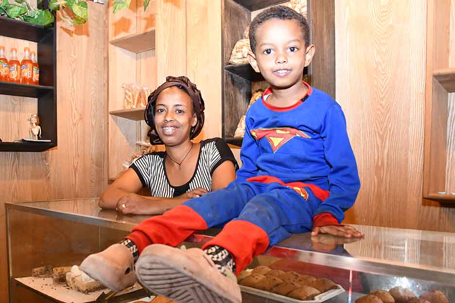 In der Bäckerei: Witwe Genet mit ihrem kleinen Sohn im Superman-Dress