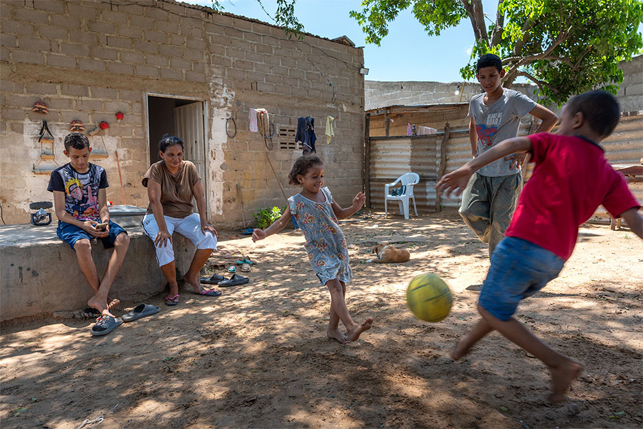 Jenny sitzt vor dem Haus, während ihre Kinder Ball spielen. Foto: Jakob Fuhr