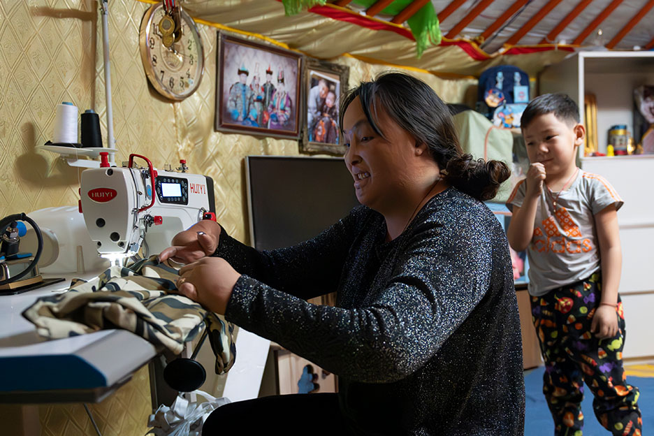 Eine Mutter näht in einer Jurte.