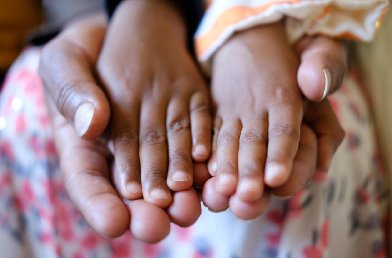 Kinderhände auf Erwachsenen-Händen.