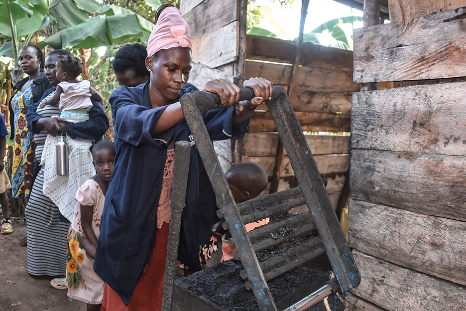 Eine Frau erstellt Biomasse-Briketts an einer Presse.