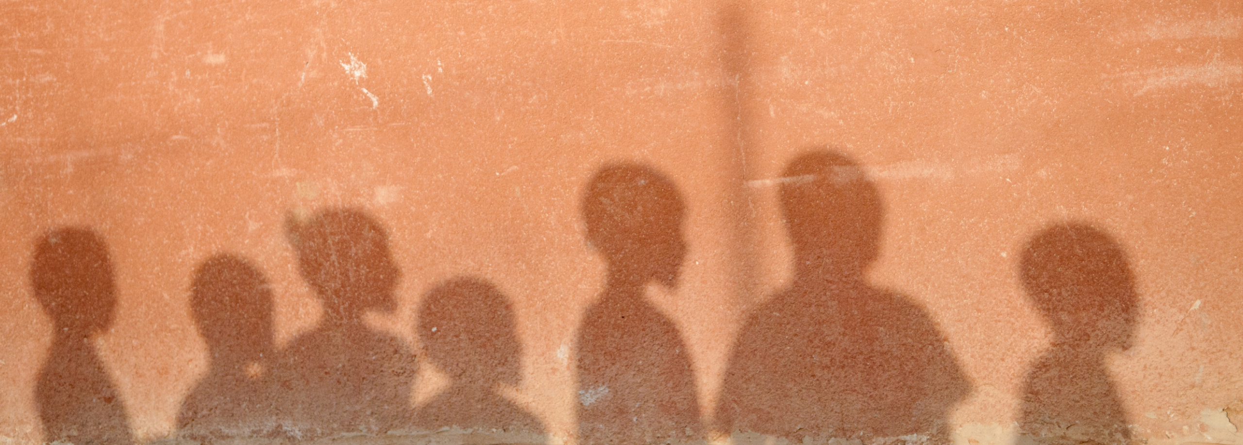 Die Schatten von 7 Kindern, die häusliche Gewalt erfahren haben, auf einer Hauswand.
