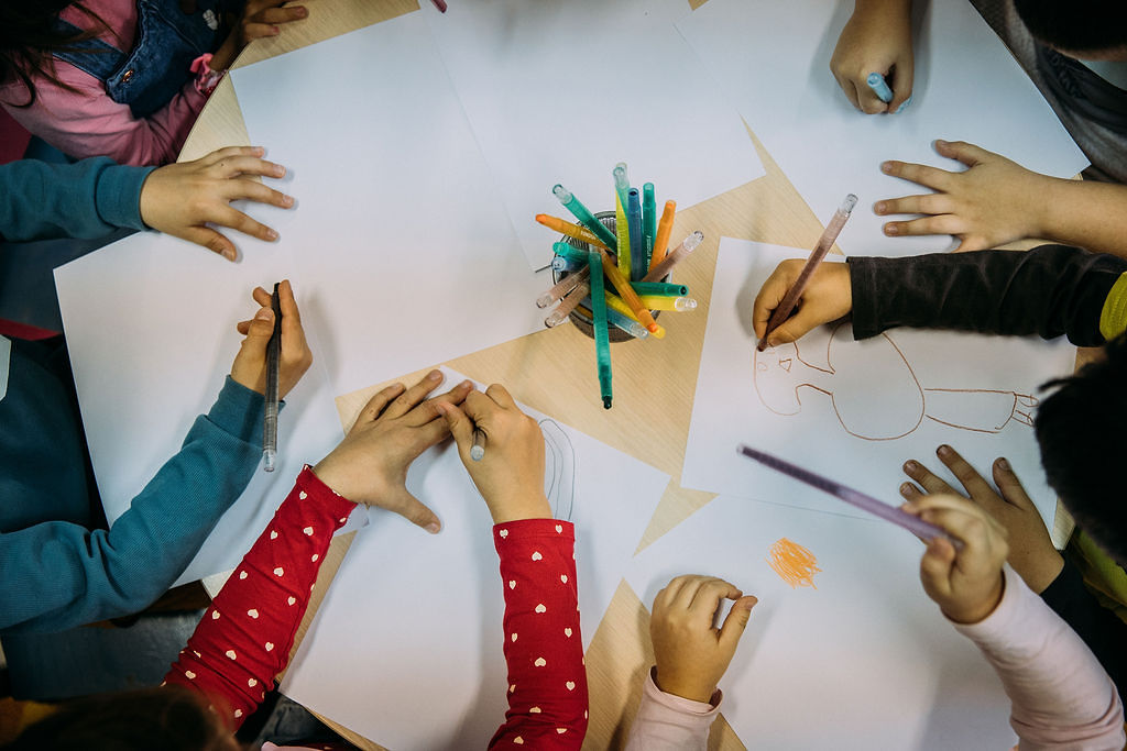 Kinderhände, die an einem Tisch Bilder malen. Foto: Alea Horst