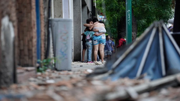 Kinder und Erwachsene liegen sich in den Armen, auf der Straße sind Trümmer zu sehen. Foto: MANAURE_QUINTERO / AFP