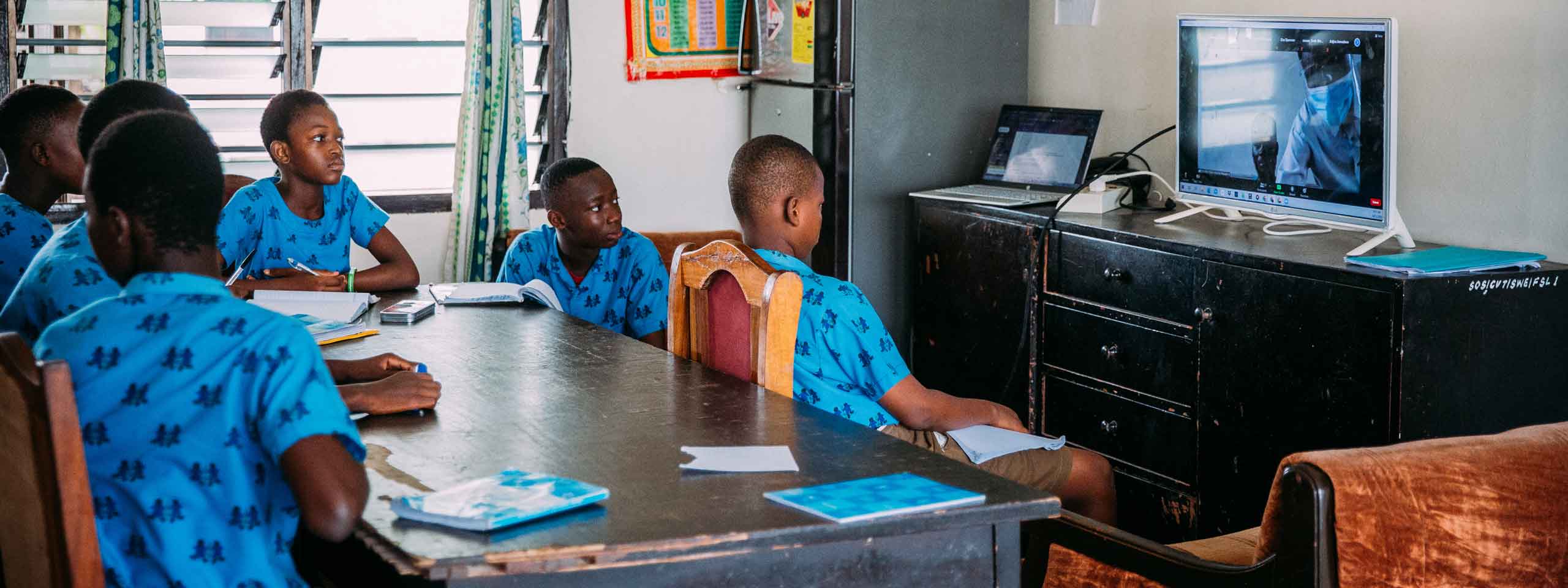 Homeschooling im SOS-Kinderdorf in Ghana: Kinder sitzen im Esszimmer vor dem Bildschirm. Foto: Alea Horst
