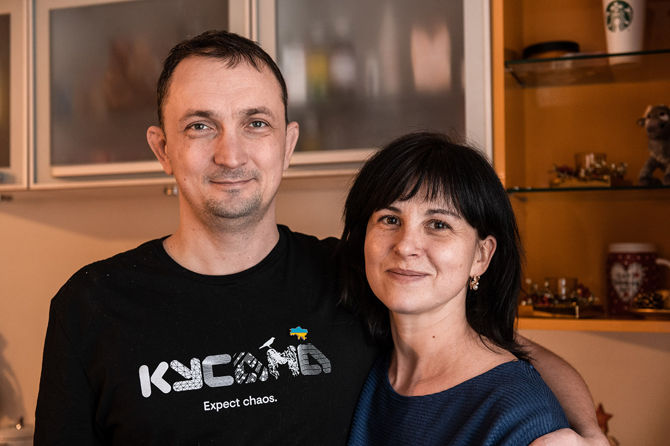 Leonid und Olha stehen Arm in Arm in ihrem neuen Wohnzimmer in Rumänien.