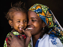 Eine junge afrikanische Mutter schmust mit ihrem Kind