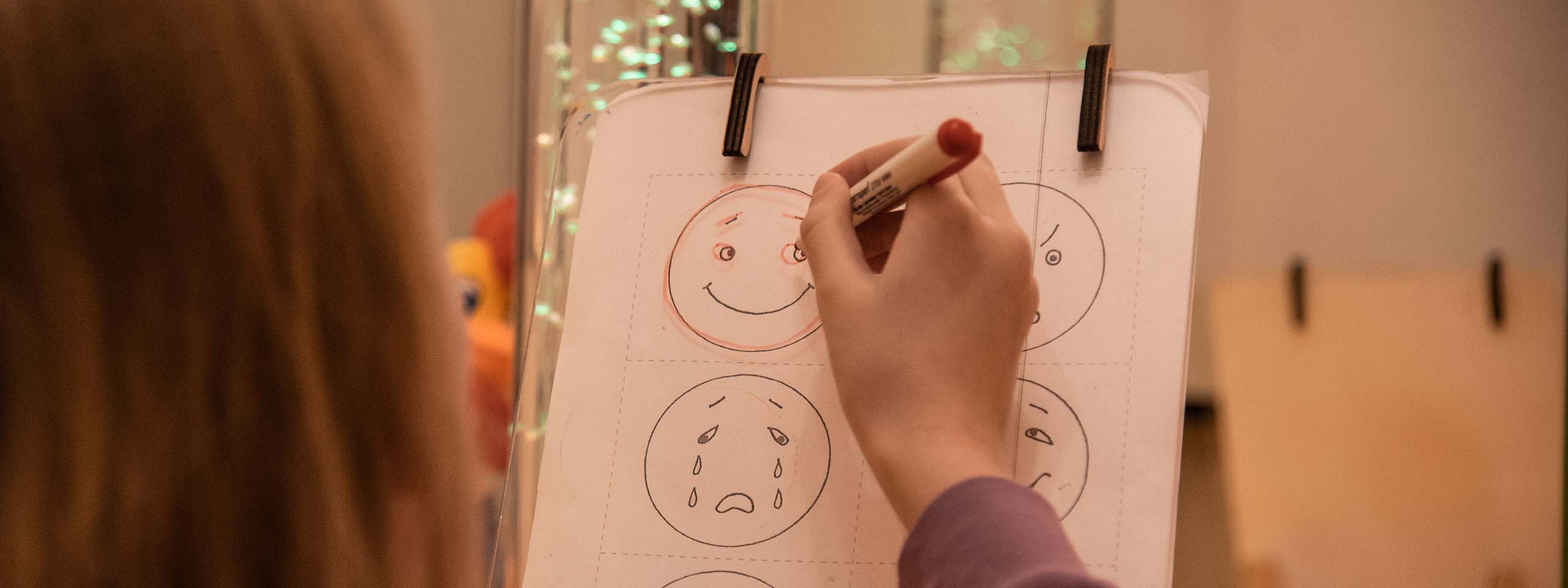 Trauer bei Kindern: Ein Kind markiert auf einem Gefühls-Chart einen lächelnden Smiley. Foto: Katerina Ilievska