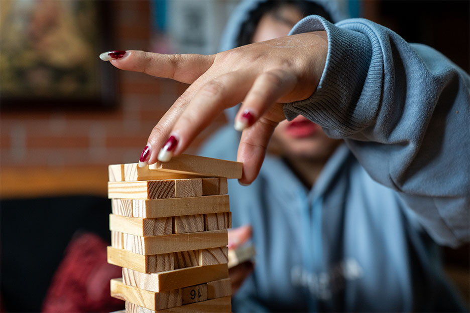Maryans Hand in Großaufnahme: Sie spielt ein Geschicklichkeitsspiel und baut einen Turm aus Holzklötzchen.