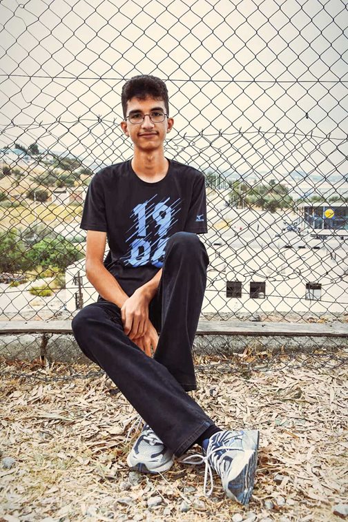 Kourosh sitzt vor einem Zaun beim Flüchtlingscamp Kara Tepe auf der griechischen Insel Lesbos.