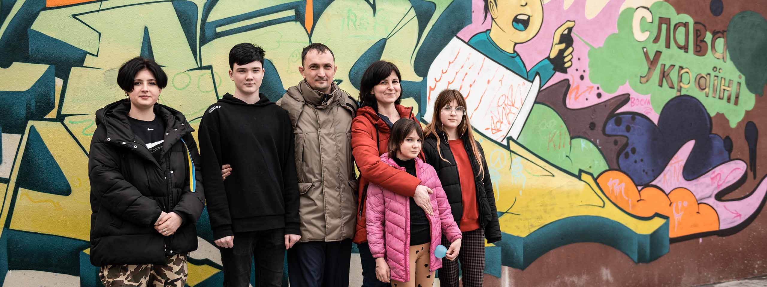 Ukrainische Familie steht vor ihrem neuen Haus im SOS-Kinderdorf Hemeius, Rumänien. 