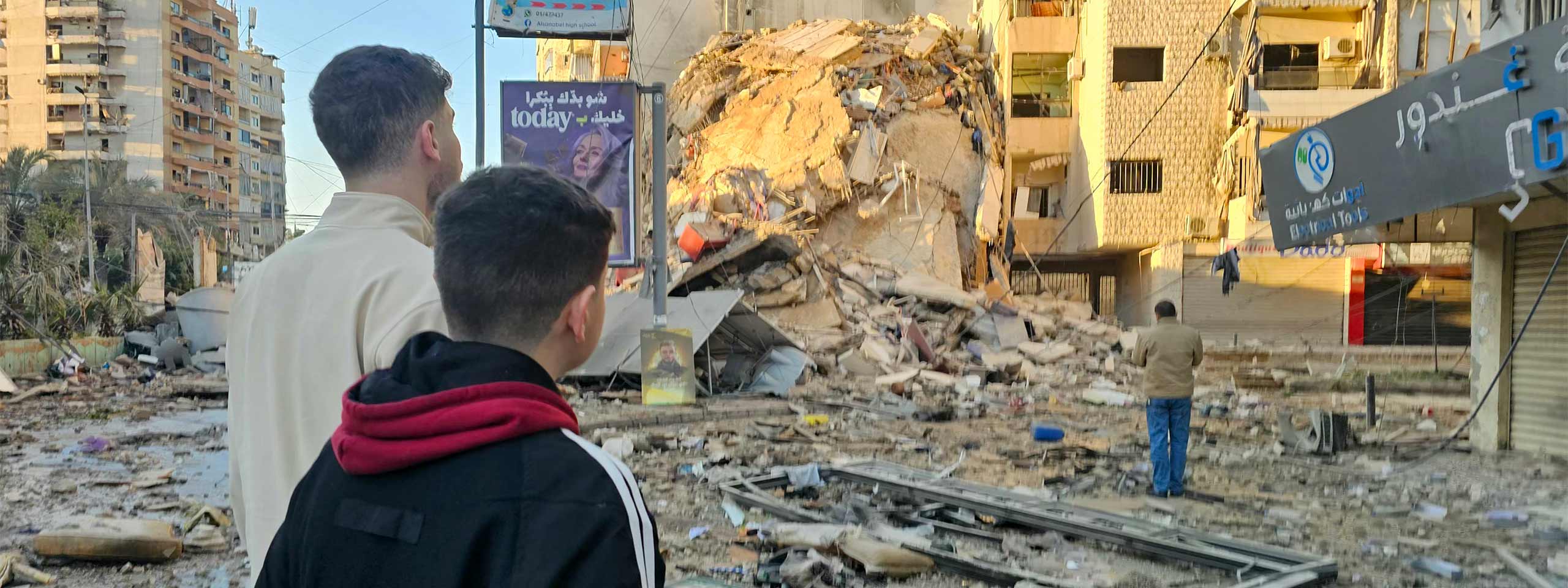 Jugendliche blicken auf Trümmer in einem Vorort Beiruts