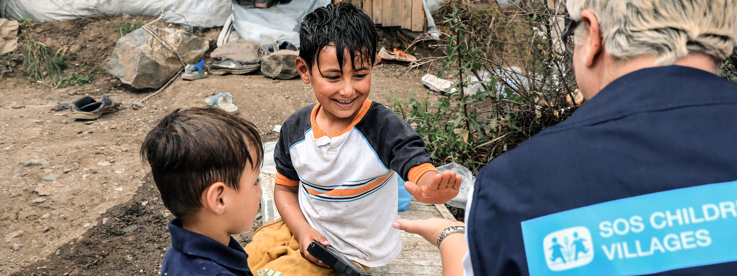 Betreuer bei der SOS-Kinderdörfer Nothilfe kümmert sich um 2 Jungs.