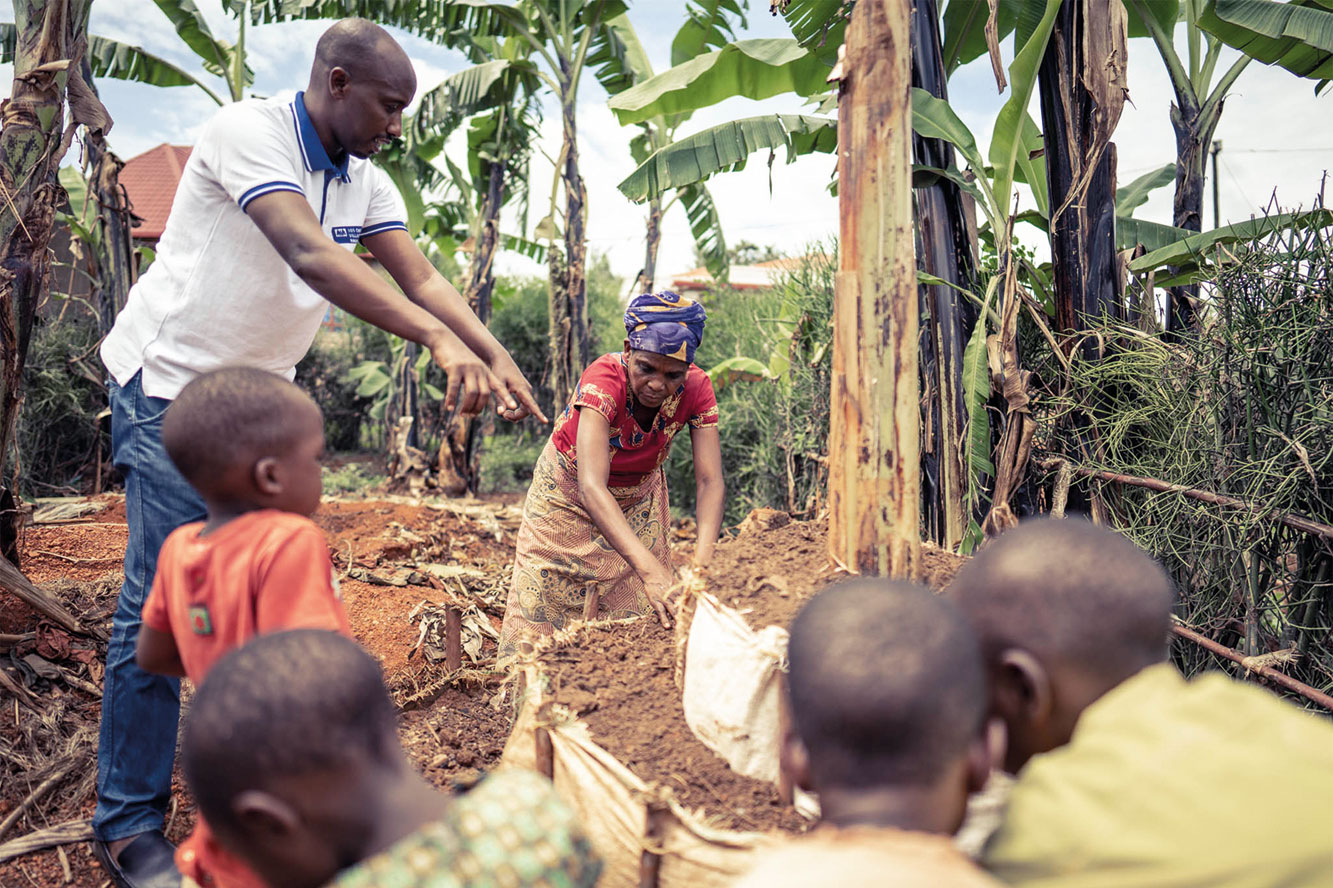 Ein Mitarbeiter der SOS-Kinderdörfer legt mit Dorothée einen Küchengarten an.