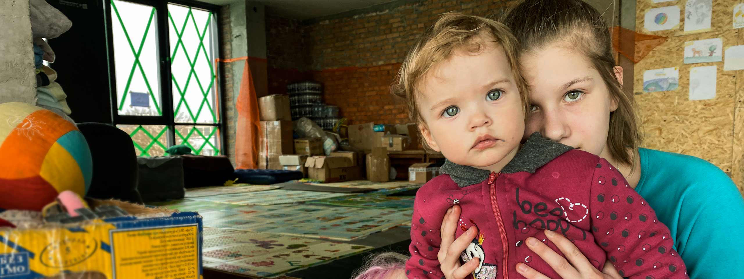 Mutter hält Kind fest, beide stammen aus dem Hilfsprojekt Ukraine, und blicken in die Kamera.