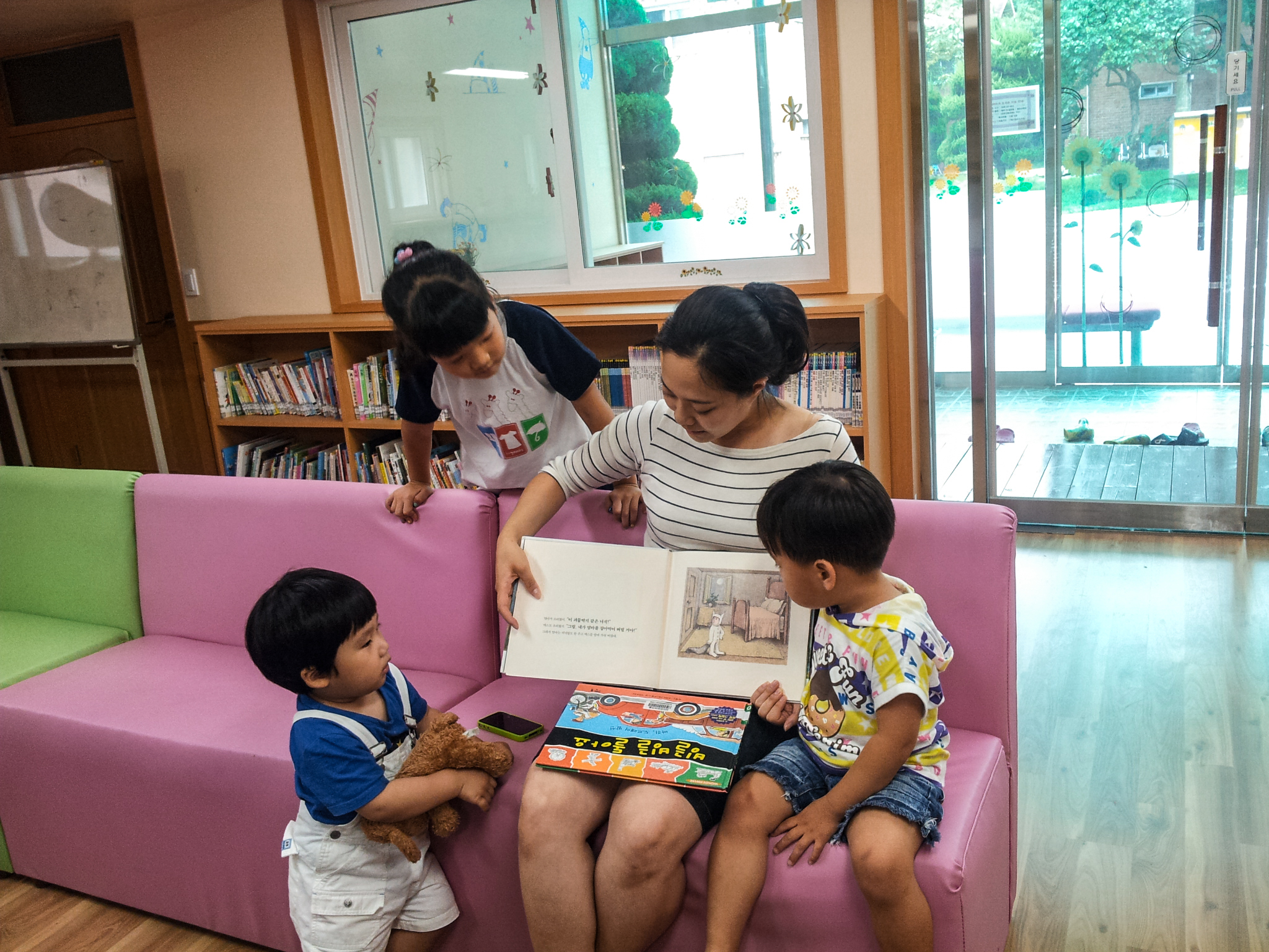 SOS-Kinder in Südkorea sehen mit ihrer SOS-Mutter ein Bilderbuch an.