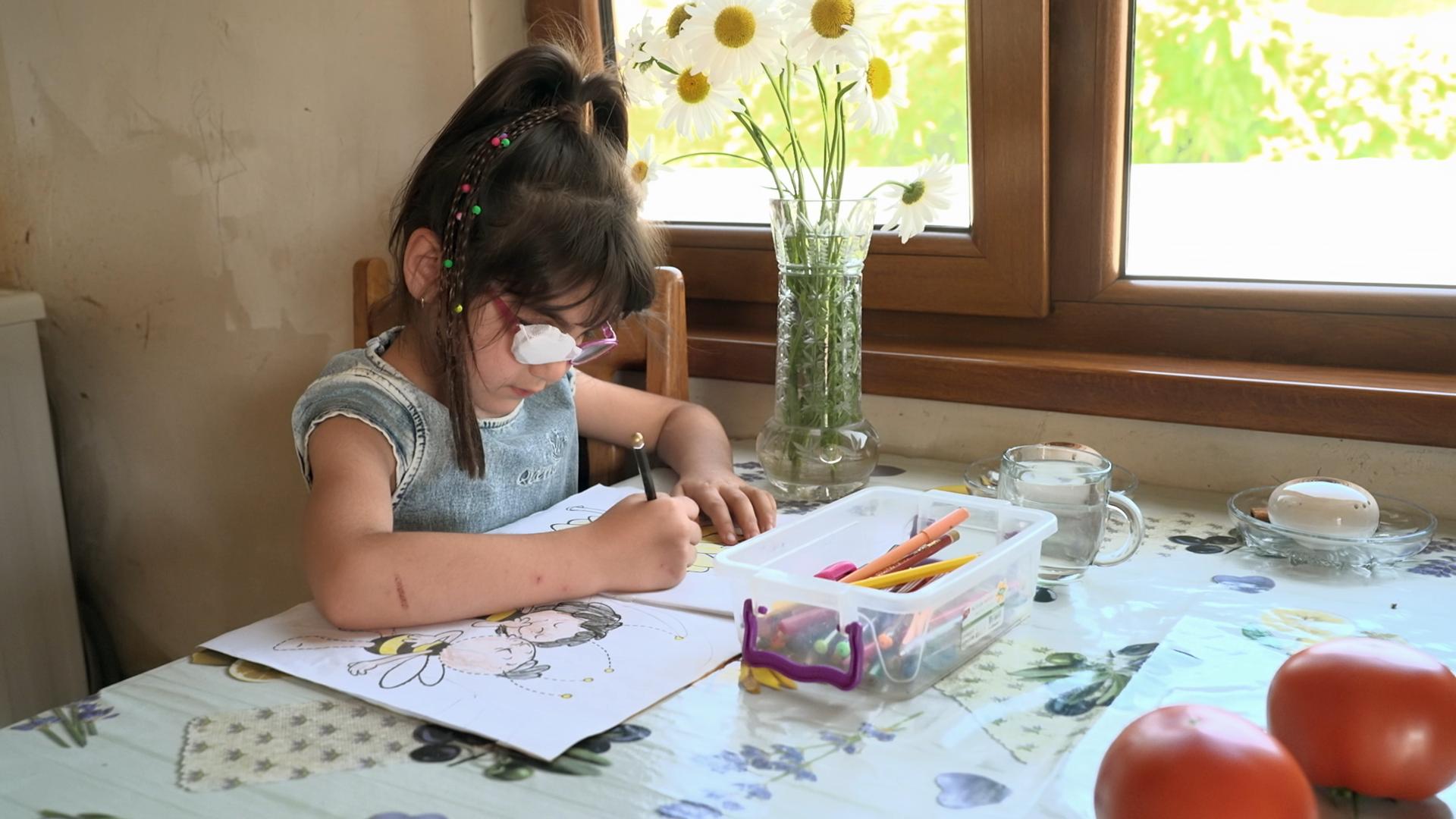 Malendes Kind in Armenien, das an einem Tisch sitzt.
