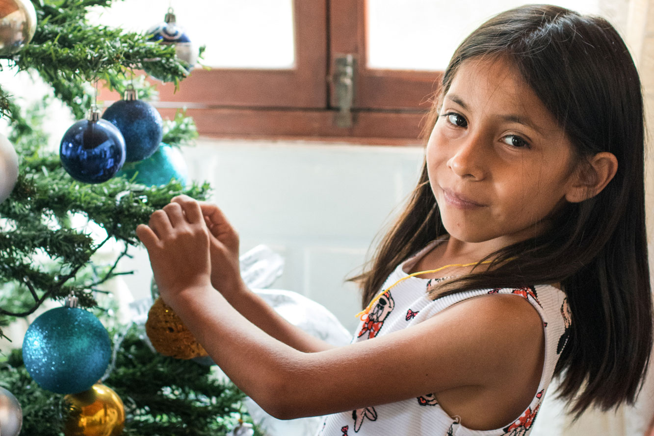 Mädchen schmückt Weihnachtsbaum