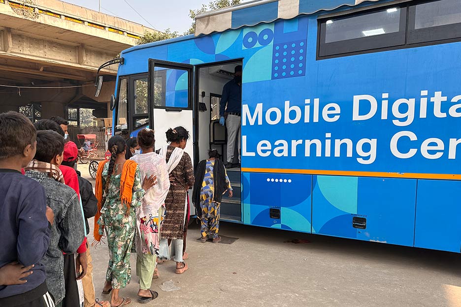 Kinder und Jugendliche haben sich einer Reihe angestellt und steigen in den Digitalen Lernbus der SOS-Kinderdörfer ein.