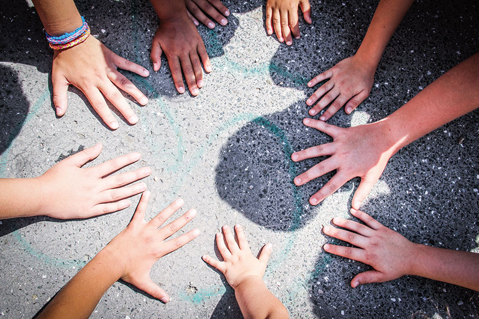 Kinderhände auf Asphalt im Kreis