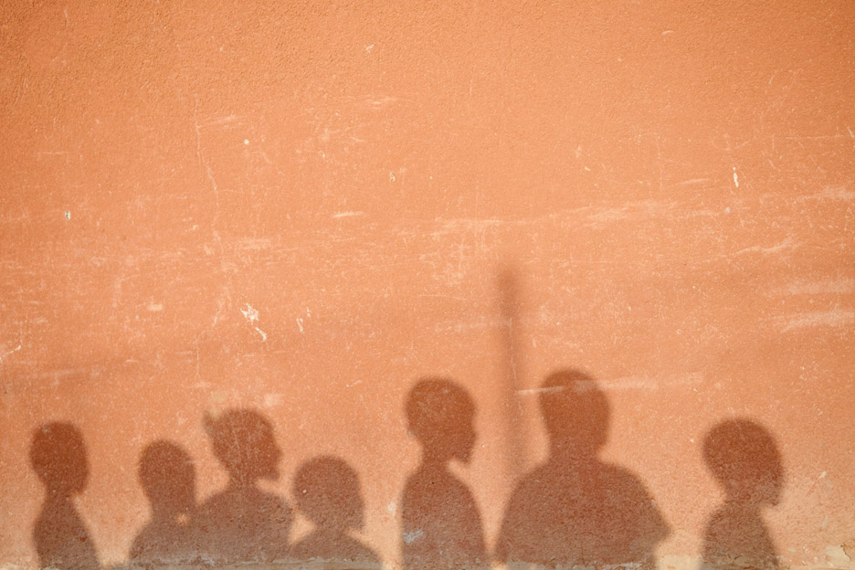 Eine hellbraune Wand mit den Schattenumrissen von sieben Kindern