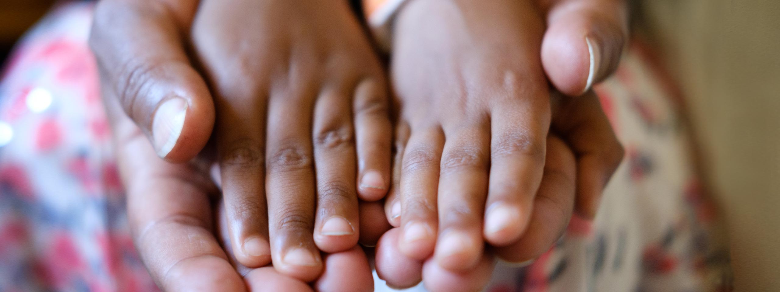 Kinderhände liegen auf Erwachsenen-Händen.