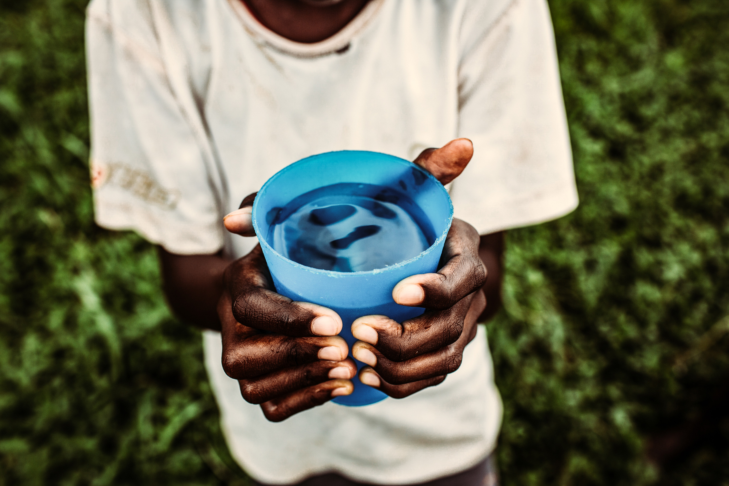 Kind hält sauberes Trinkwasser in einem Becher, das gespendet wurde.