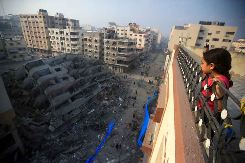 Ein palästinensisches Mädchen in Gaza blickt auf Gebäude, die durch einen Bombenangriff zerstört wurden. Foto: Mohamed Zaanoun / Middle East Images via AFP