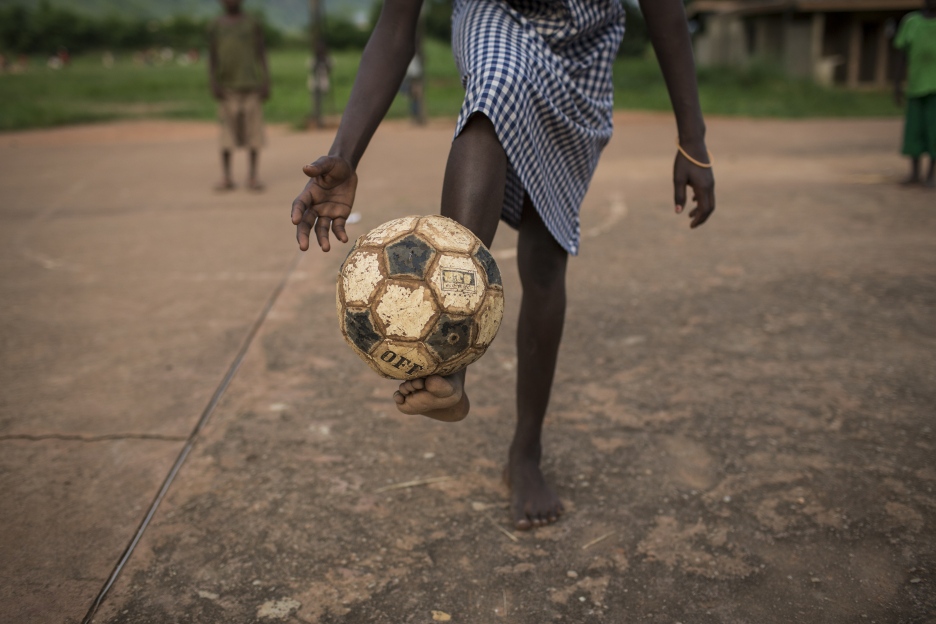 Ein Mädchen balanciert einen Fußball auf ihrem Fuß.