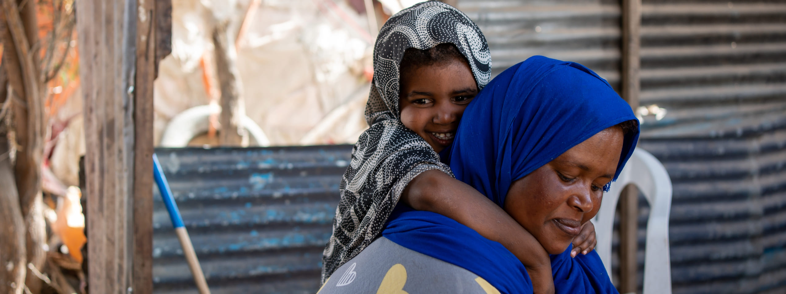Somaliland: Kind hält sich am Rücken der Mutter fest und lacht, Foto: Lydia Mantler