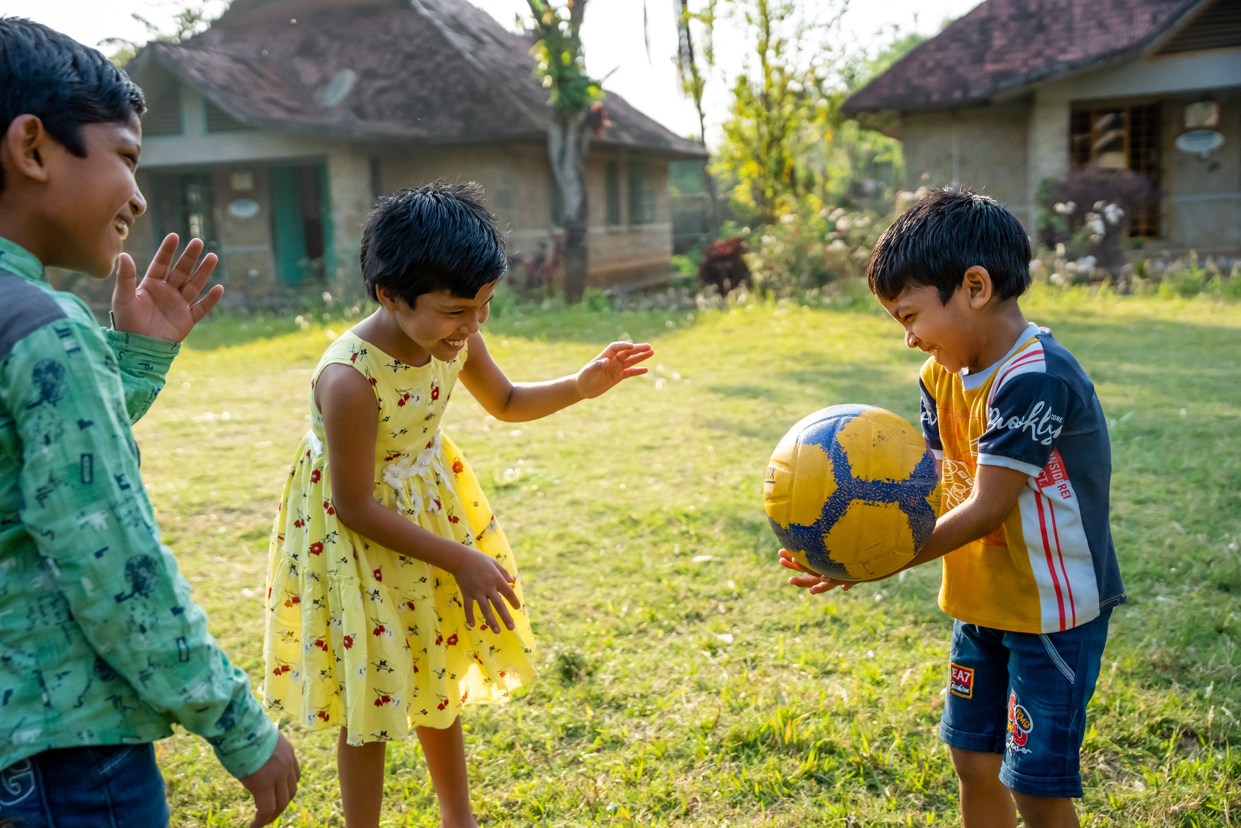Kinder spielen auf Wiese mit Ball