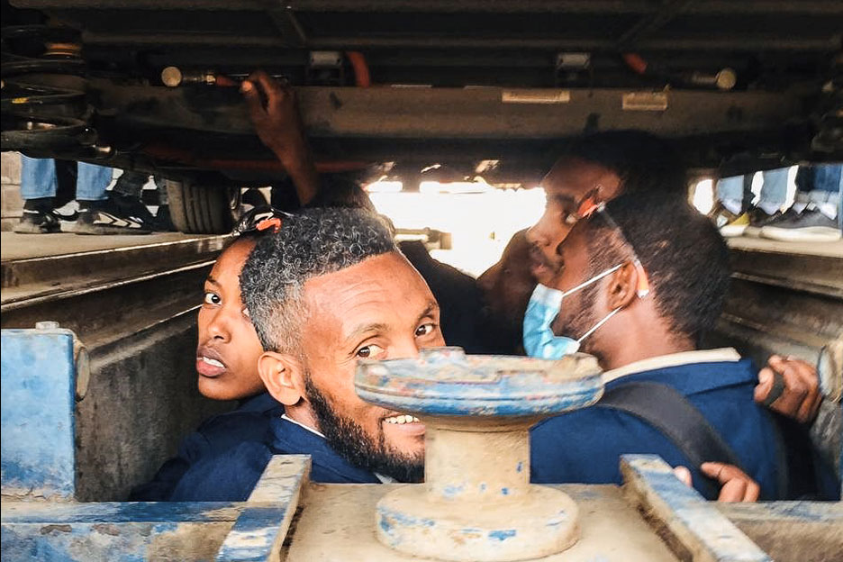 Auszuibildende inspizieren ein E-Auto in der Werkstatt.