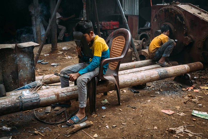 Kinderarbeit in Bangladesh: Die beiden Jungen im Hafen von Dhaka helfen mit, Rohstoffe aus alten Schiffen zu gewinnen, woraus neue Schiffsteile wie Antriebswellen gefertigt werden. Über drei Millionen Kinder in Bangladesch verrichten Kinderarbeit, rund 1,25 Millionen von ihnen sogar unter gesundheitsgefährdenden Bedingungen. Foto: SOS-Kinderdörfer/Alea Horst