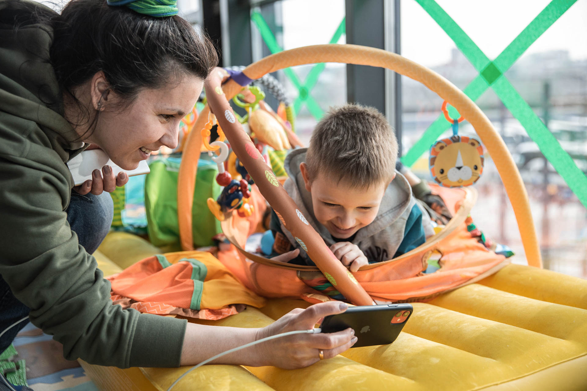 Eine Mutter zeigt ihrem Kind etwas auf dem Handy. Beide lächeln.