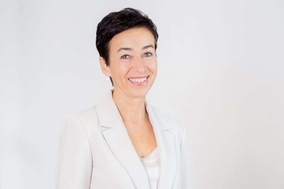 Ein kleiner Junge und eine Erwachsene schauen, an einem Abhang stehend, in einen Wald.