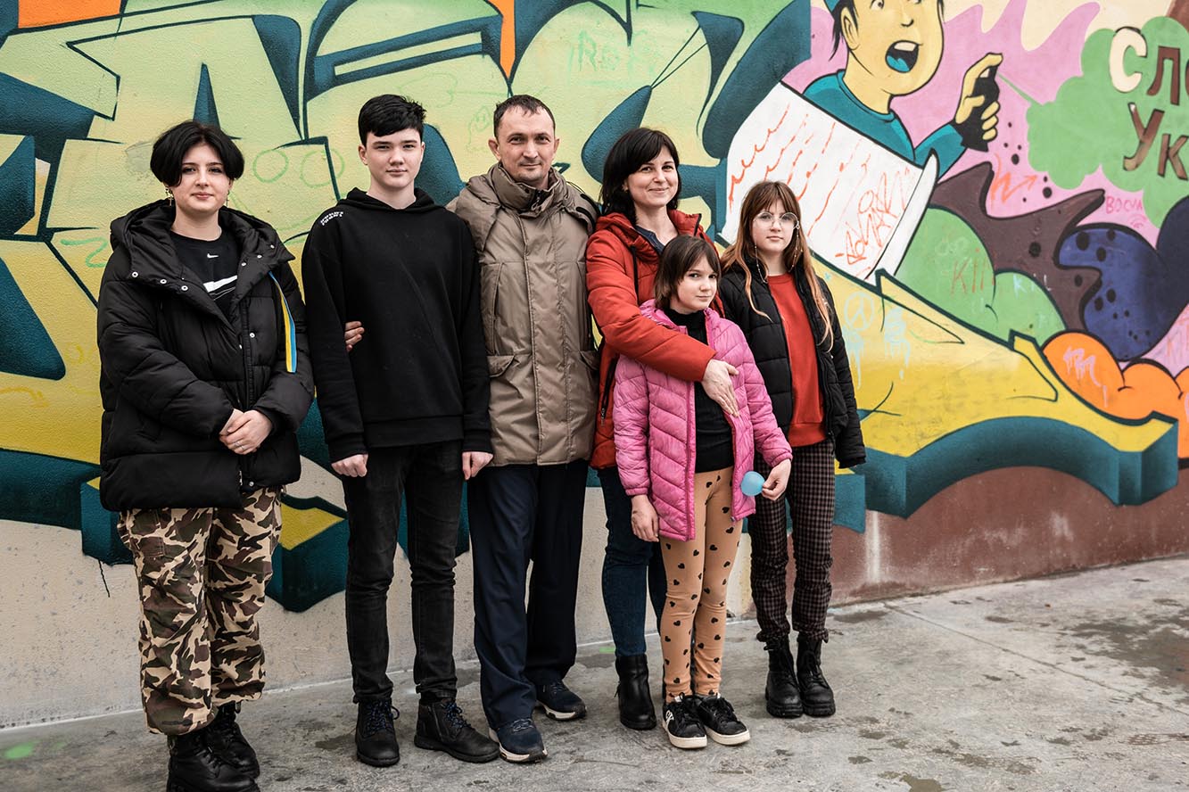 Ukrainische Familie steht vor ihrem neuen Haus im SOS-Kinderdorf Hemeius, Rumänien. 