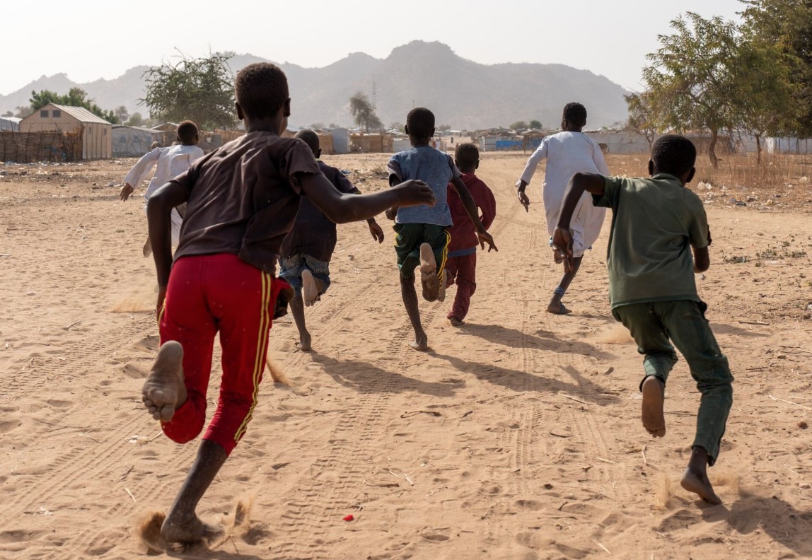 Eine Gruppe von Jungen rennt einen sandigen Weg entlang. 