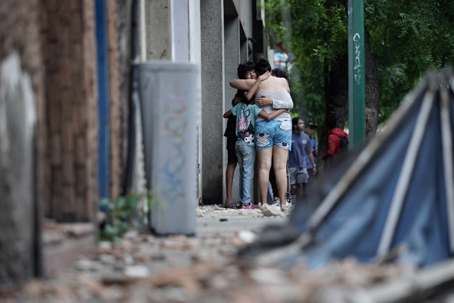 Kinder und Erwachsene liegen sich in den Armen, auf der Straße sind Trümmer zu sehen. Foto: MANAURE_QUINTERO / AFP