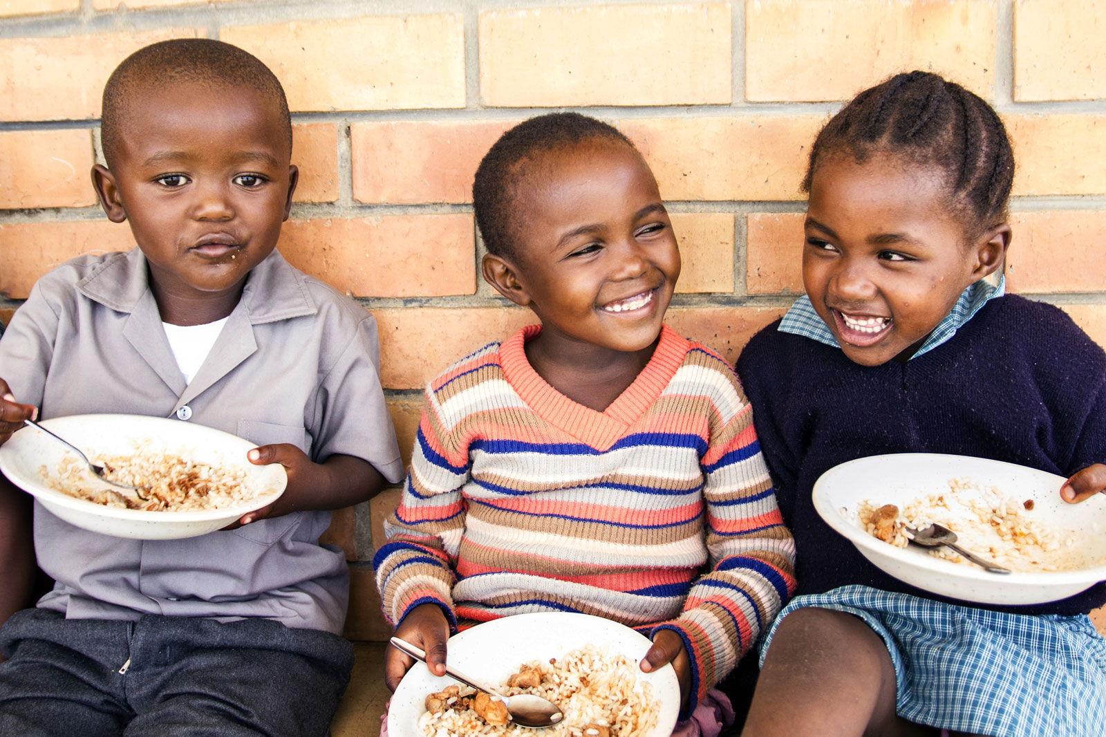 Kinder, die essen, freuen sich über gespendetes Essen.