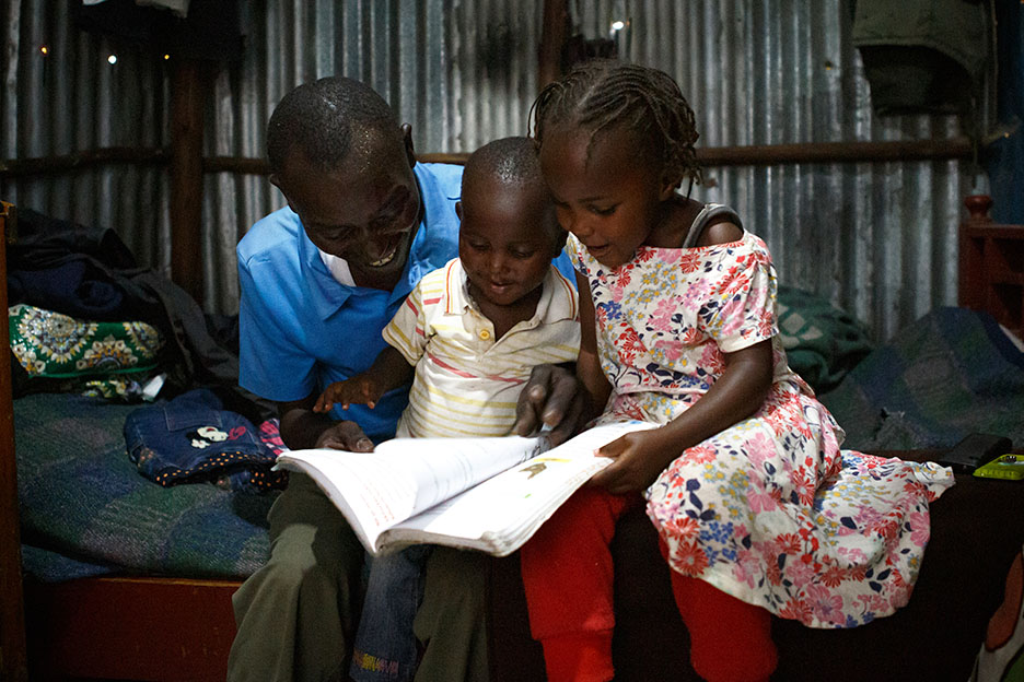 Vater aus Kenia liest seinen Kindern vor.