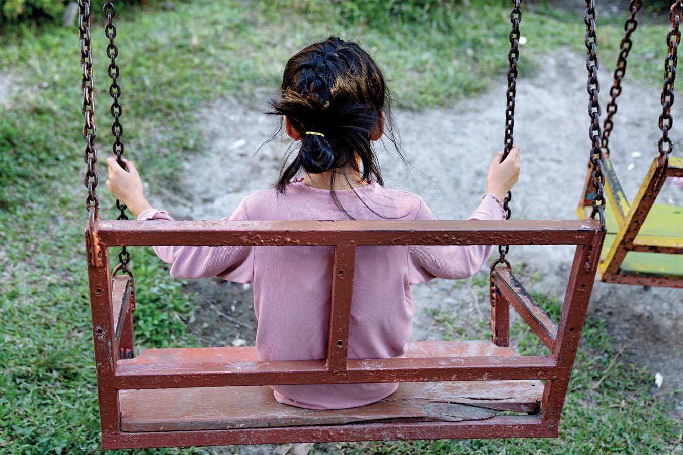 Mädchen, ein Waisenkind, sitzt alleine auf einer Schaukel. Foto: Agnete Schlichtkrul