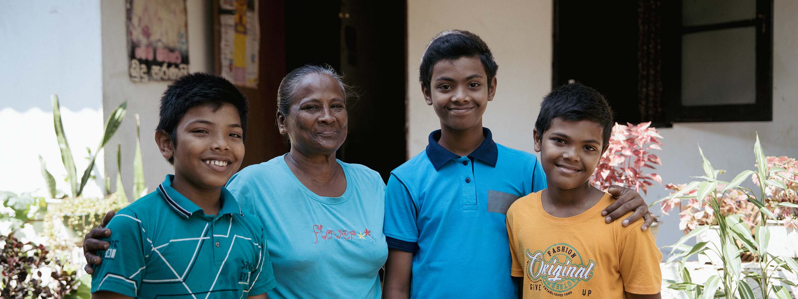 Leena steht mit ihren drei Enkeln vor dem Haus.