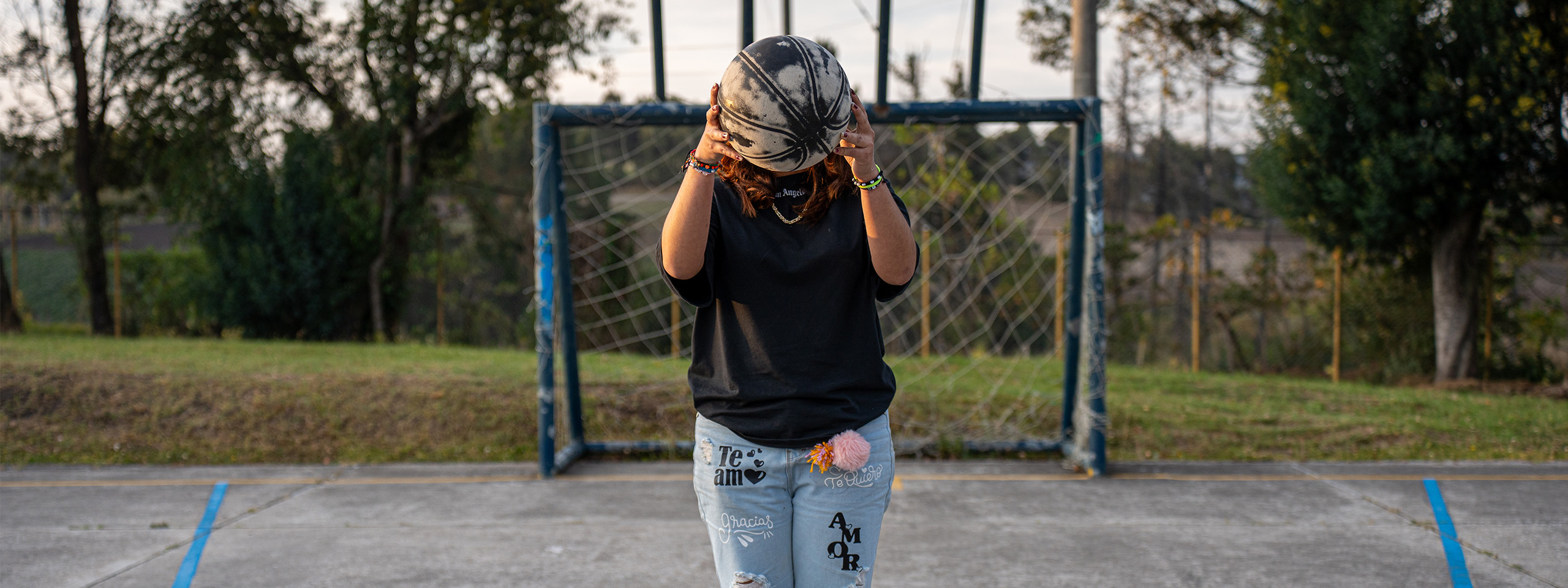 Maryan steht auf einem Sportplatz und hält einen Ball.