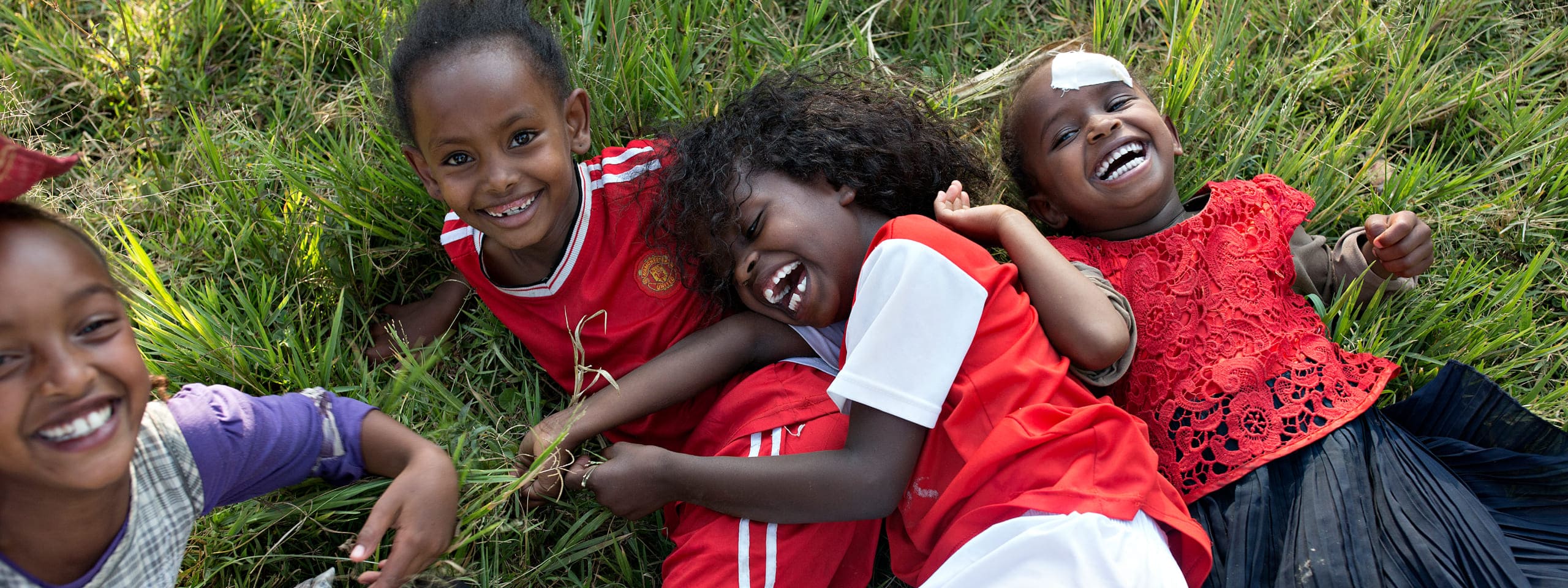 Kinder liegen auf Wiese und lachen