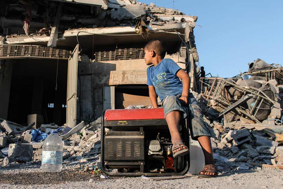 Kind sitzt auf Trümmern eines zerstörten Hauses